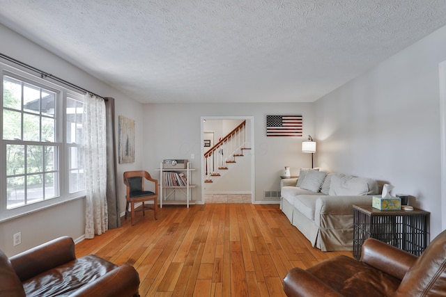 5255 Dory Ln, Columbus, OH 43235 - living room featuring stairs, light wood-type flooring, a textured ceiling, and baseboards
