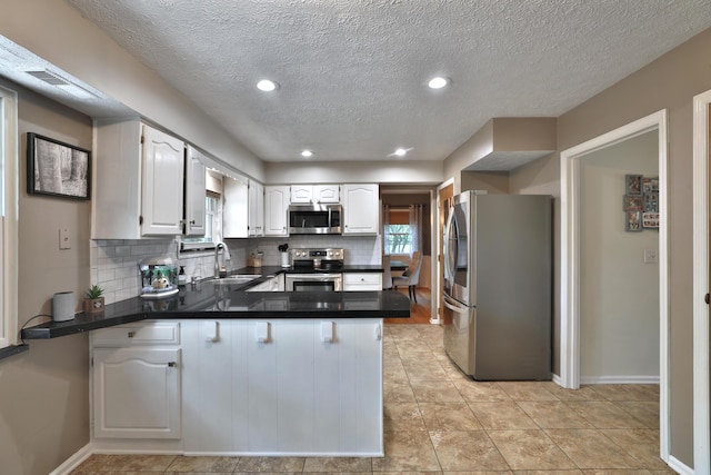 5255 Dory Ln, Columbus, OH 43235 - kitchen with appliances with stainless steel finishes, a peninsula, a sink, backsplash, and dark countertops