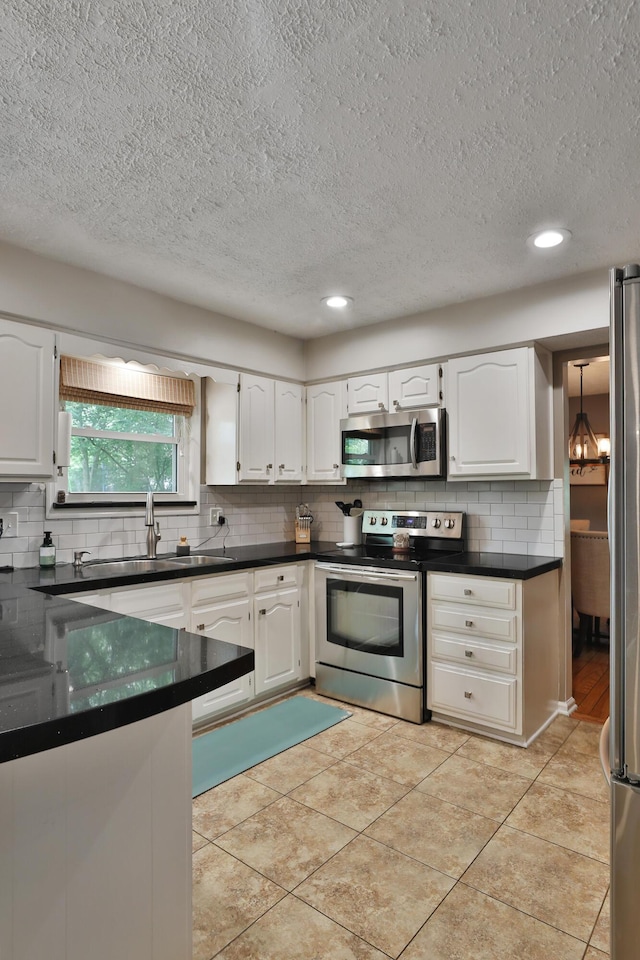 5255 Dory Ln, Columbus, OH 43235 - kitchen with appliances with stainless steel finishes, a sink, dark countertops, decorative backsplash, and a textured ceiling