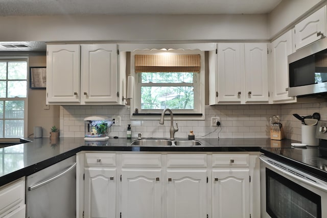 5255 Dory Ln, Columbus, OH 43235 - kitchen featuring appliances with stainless steel finishes, a sink, white cabinets, dark countertops, and decorative backsplash