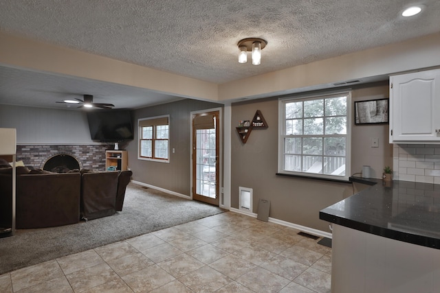 5255 Dory Ln, Columbus, OH 43235 - kitchen with dark countertops, white cabinetry, a fireplace, light carpet, and baseboards