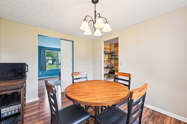 6588 Ethan Dr, Reynoldsburg, OH 43068 - dining space featuring a chandelier, wood finished floors, baseboards, and a textured ceiling