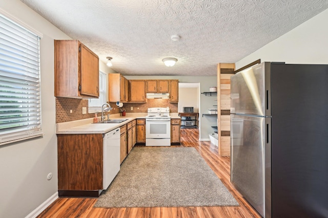 6588 Ethan Dr, Reynoldsburg, OH 43068 - kitchen featuring white appliances, a sink, under cabinet range hood, light wood-type flooring, and light countertops