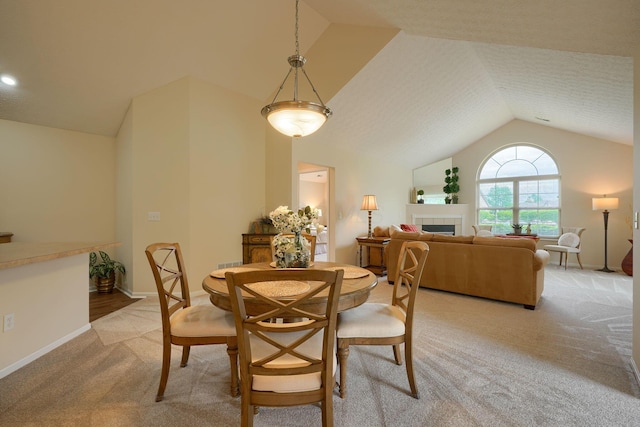 6973 Falls View Cir, Delaware, OH 43015 - dining area with lofted ceiling, light colored carpet, a tiled fireplace, and baseboards