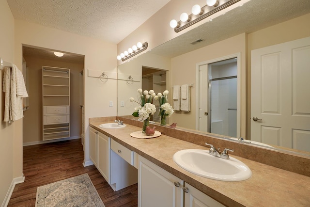 6973 Falls View Cir, Delaware, OH 43015 - bathroom featuring double vanity, wood finished floors, a textured ceiling, a shower with shower door, and baseboards