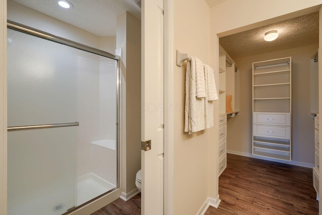 6973 Falls View Cir, Delaware, OH 43015 - full bathroom featuring a textured ceiling, a stall shower, a closet, wood finished floors, and toilet