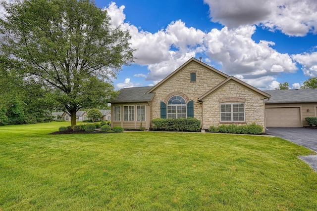 6973 Falls View Cir, Delaware, OH 43015 - view of front of house featuring asphalt driveway, a front yard, stone siding, and a garage