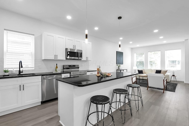 1191 Seymour Ave, Columbus, OH 43206 - kitchen with stainless steel appliances, a breakfast bar, light wood-type flooring, decorative backsplash, and a sink