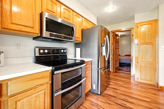 19160 Coshocton Rd, Mount Vernon, OH 43050 - kitchen featuring stainless steel appliances, light wood finished floors, light countertops, and a textured ceiling