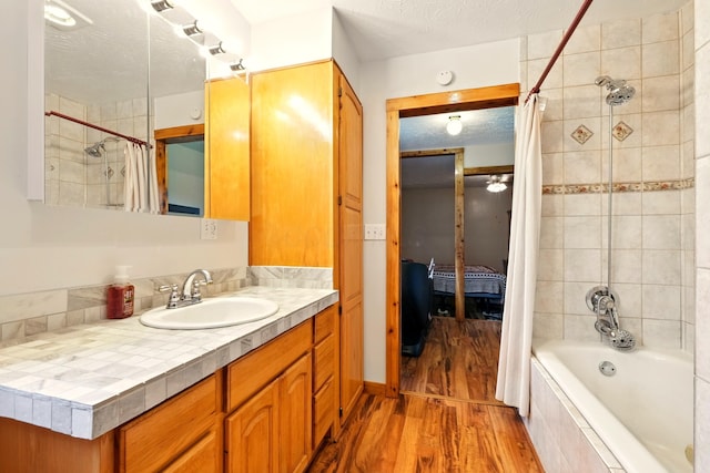 19160 Coshocton Rd, Mount Vernon, OH 43050 - ensuite bathroom featuring tiled shower / bath, wood finished floors, vanity, a textured ceiling, and a ceiling fan