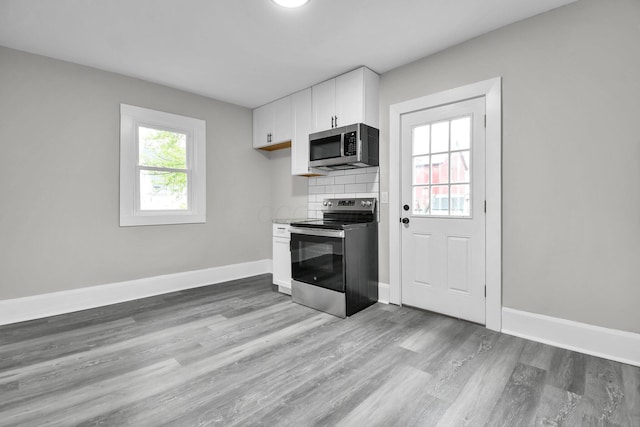 44 W 4th St, Fredericktown, OH 43019 - kitchen featuring stainless steel appliances, white cabinetry, light wood-type flooring, and decorative backsplash