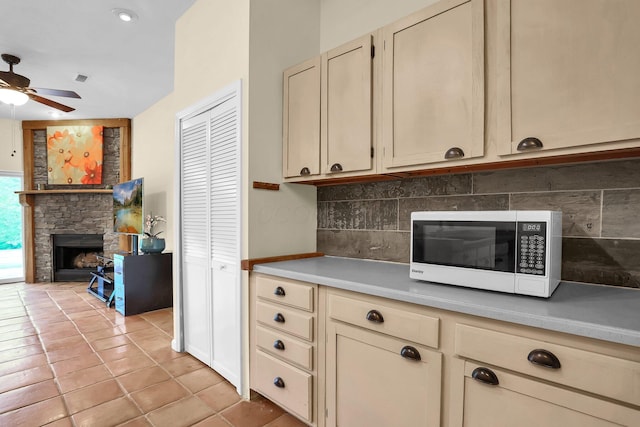 2149 Baptist Hill Rd, Chillicothe, OH 45601 - kitchen featuring white microwave, cream cabinetry, a stone fireplace, and a ceiling fan