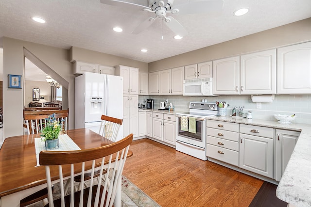 4995 Softwood Ct, Westerville, OH 43081 - kitchen featuring white appliances, white cabinets, ceiling fan, light wood finished floors, and decorative backsplash