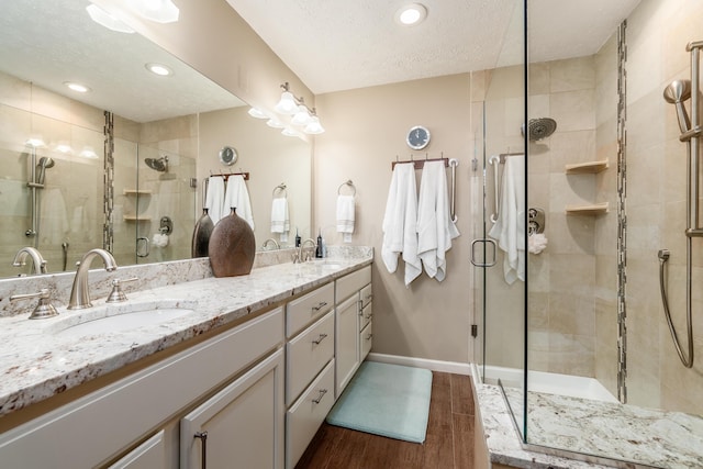 4995 Softwood Ct, Westerville, OH 43081 - bathroom with double vanity, wood finished floors, a stall shower, a textured ceiling, and baseboards