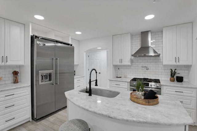 2615 NW Blvd, Upper Arlington, OH 43221 - kitchen with stainless steel appliances, wall chimney range hood, a sink, white cabinetry, and backsplash