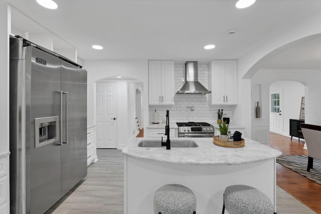 2615 NW Blvd, Upper Arlington, OH 43221 - kitchen with appliances with stainless steel finishes, wall chimney exhaust hood, a sink, backsplash, and white cabinetry