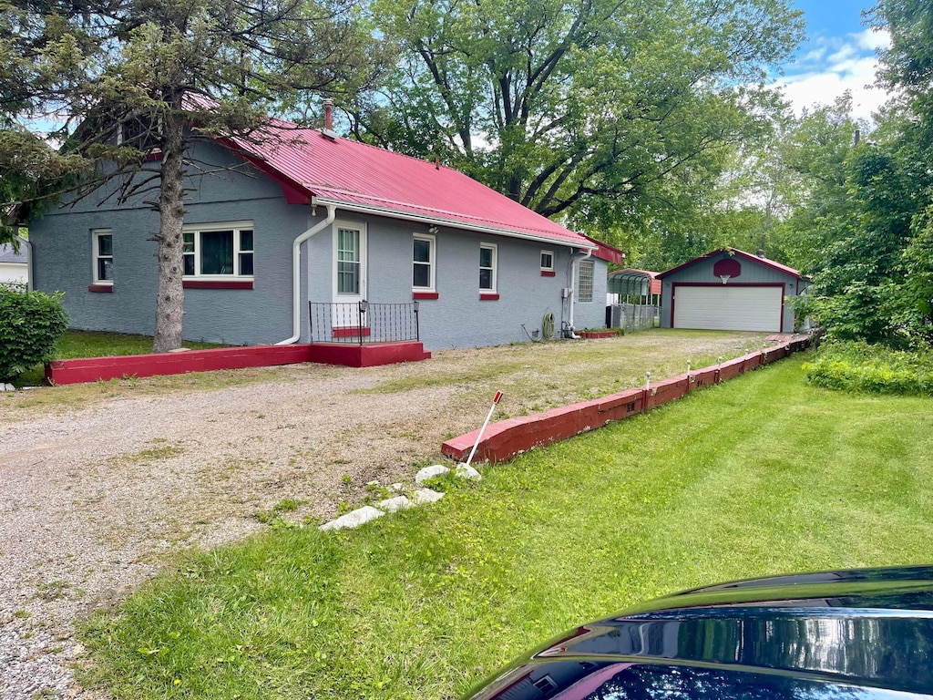 13424 Ivy Rd NE, Thornville, OH 43076 - view of property exterior with a garage, an outdoor structure, a lawn, stucco siding, and metal roof