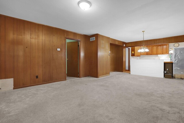 13424 Ivy Rd NE, Thornville, OH 43076 - unfurnished living room featuring wooden walls, a chandelier, and light colored carpet