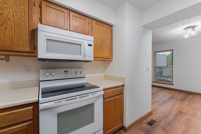 406 Olentangy Forest Dr Unit 9B, Columbus, OH 43214 - kitchen featuring white appliances, brown cabinetry, wood finished floors, light countertops, and a textured ceiling