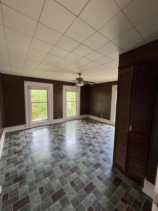627 N Main St, Utica, OH 43080 - empty room with wood walls, ceiling fan, a paneled ceiling, and baseboards