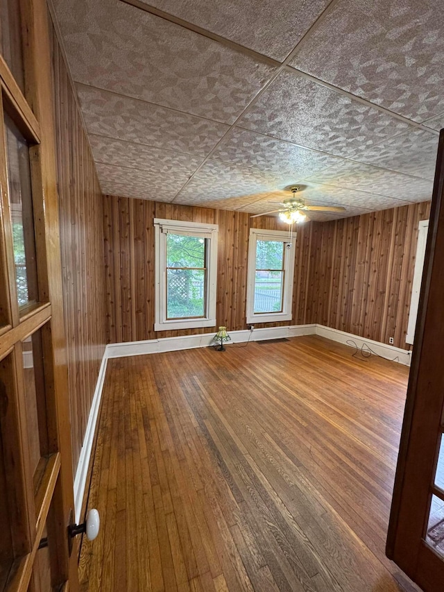 627 N Main St, Utica, OH 43080 - unfurnished room with wood-type flooring, ceiling fan, wooden walls, an ornate ceiling, and baseboards