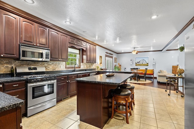 15027 King Rd, Howard, OH 43028 - kitchen with appliances with stainless steel finishes, light tile patterned flooring, backsplash, a breakfast bar area, and a center island