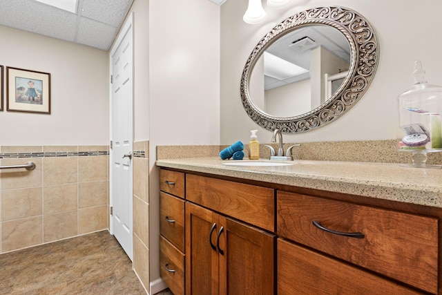 15027 King Rd, Howard, OH 43028 - bathroom with vanity, a wainscoted wall, tile walls, and a paneled ceiling
