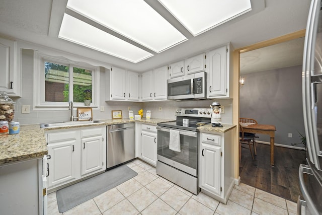 4129 Leitrim Ct, Dublin, OH 43016 - kitchen with stainless steel appliances, a sink, light tile patterned floors, white cabinetry, and light stone countertops