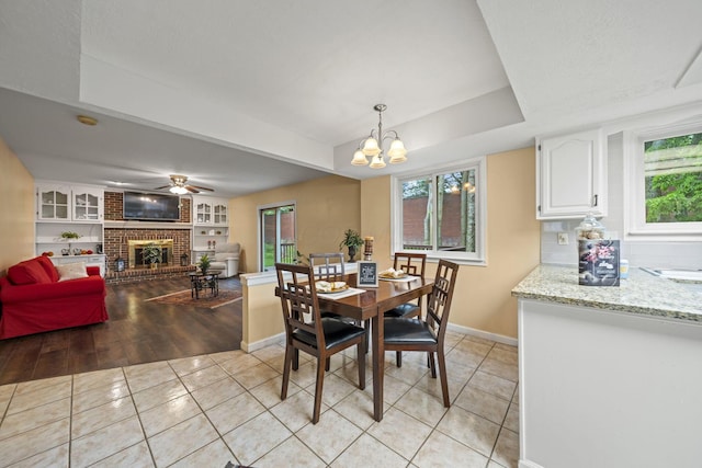 4129 Leitrim Ct, Dublin, OH 43016 - dining room with light tile patterned floors, baseboards, a brick fireplace, a raised ceiling, and a chandelier