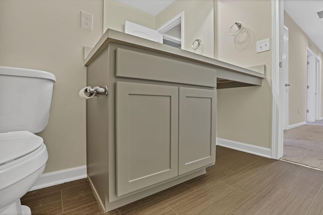 233 Dowler Dr, South Bloomfield, OH 43103 - half bathroom featuring toilet, vanity, baseboards, and wood finished floors