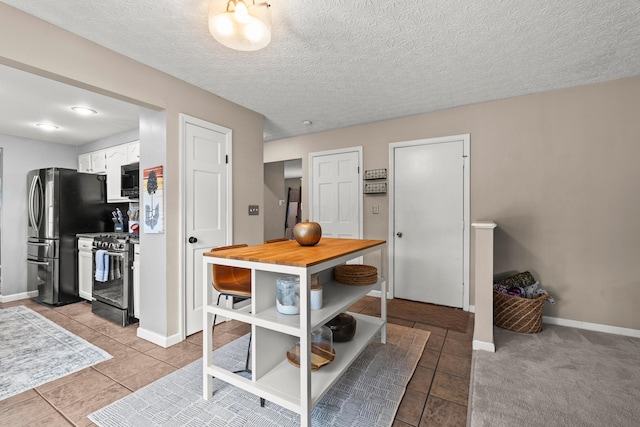1997 Sutter Pkwy, Dublin, OH 43016 - kitchen with gas range, freestanding refrigerator, white cabinets, baseboards, and a textured ceiling
