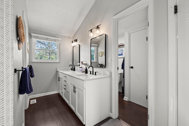 1997 Sutter Pkwy, Dublin, OH 43016 - bathroom with double vanity, wood finished floors, toilet, vaulted ceiling, and a textured ceiling