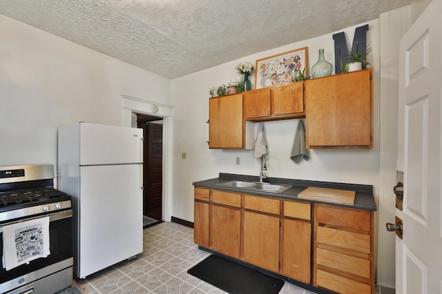2045 N 4th St, Columbus, OH 43201 - kitchen with gas range, freestanding refrigerator, a sink, dark countertops, and a textured ceiling