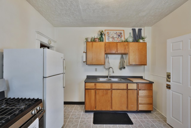 2045 N 4th St, Columbus, OH 43201 - kitchen with stainless steel gas stove, a sink, brown cabinetry, a textured ceiling, and dark countertops