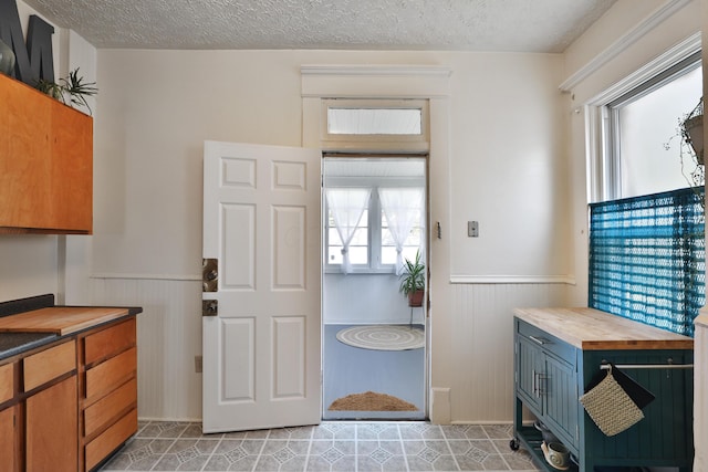 2045 N 4th St, Columbus, OH 43201 - kitchen with butcher block counters, a wainscoted wall, a textured ceiling, light tile patterned flooring, and brown cabinets