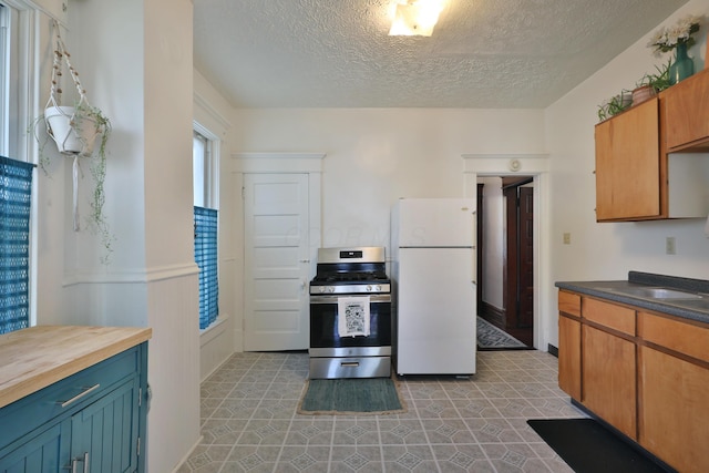 2045 N 4th St, Columbus, OH 43201 - kitchen with freestanding refrigerator, stainless steel gas stove, a textured ceiling, and wooden counters
