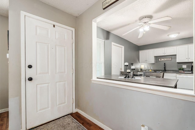 4419 Trindel Way, Columbus, OH 43231 - kitchen with a textured ceiling, dishwasher, dark wood-type flooring, baseboards, and white cabinetry