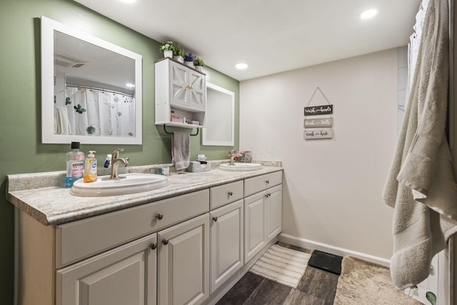 21171 River Rd, Circleville, OH 43113 - full bathroom featuring double vanity, wood finished floors, baseboards, and recessed lighting