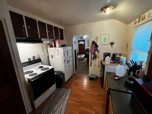 2428 Bancroft St, Columbus, OH 43211 - kitchen with white appliances, range hood, arched walkways, wood finished floors, and dark brown cabinetry