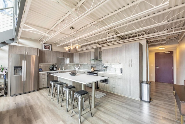 367 Auden Ave Unit 306, Columbus, OH 43215 - kitchen with appliances with stainless steel finishes, wall chimney exhaust hood, a kitchen bar, decorative backsplash, and a high ceiling