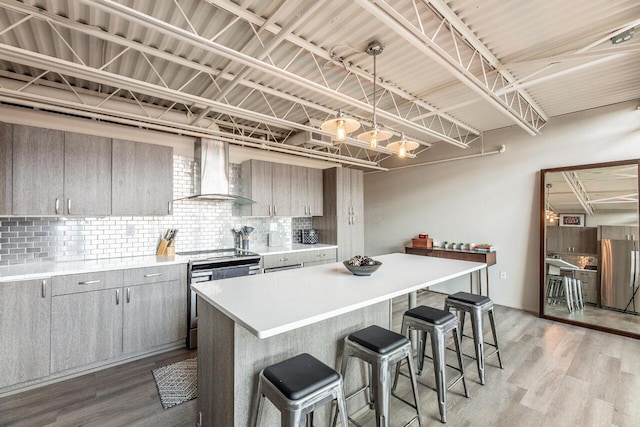 367 Auden Ave Unit 306, Columbus, OH 43215 - kitchen with wall chimney range hood, appliances with stainless steel finishes, gray cabinetry, tasteful backsplash, and light wood-type flooring
