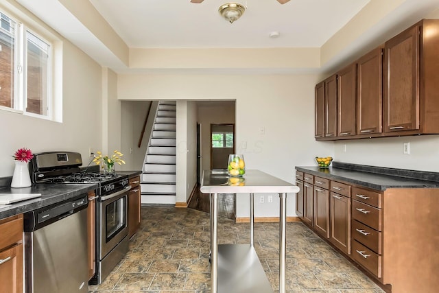 471 Southwood Ave, Columbus, OH 43207 - kitchen with appliances with stainless steel finishes, dark countertops, stone finish floors, a ceiling fan, and brown cabinetry