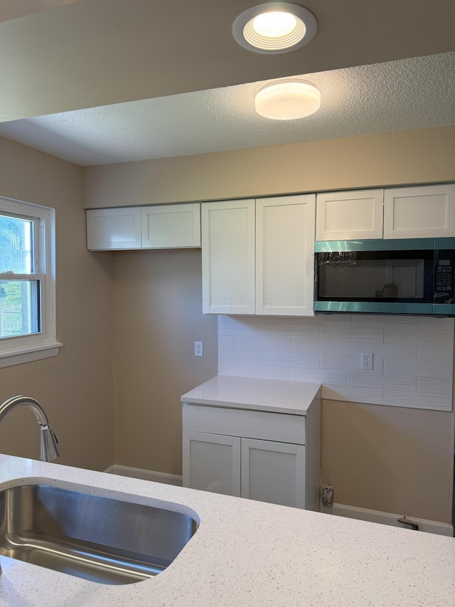 5123 Jameson Dr, Columbus, OH 43232 - kitchen with a sink, white cabinetry, backsplash, and light stone counters