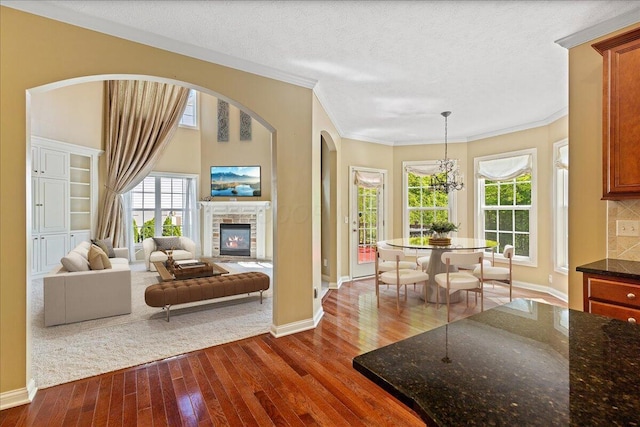 3144 Abbey Knoll Dr, Lewis Center, OH 43035 - living area featuring dark wood finished floors, baseboards, ornamental molding, a fireplace, and arched walkways
