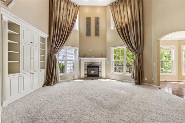 3144 Abbey Knoll Dr, Lewis Center, OH 43035 - unfurnished living room featuring a towering ceiling, plenty of natural light, arched walkways, and a stone fireplace