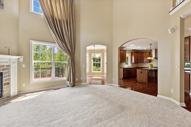 3144 Abbey Knoll Dr, Lewis Center, OH 43035 - unfurnished living room featuring dark colored carpet, a towering ceiling, arched walkways, and baseboards
