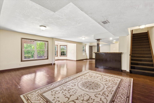 3144 Abbey Knoll Dr, Lewis Center, OH 43035 - unfurnished living room with a textured ceiling, baseboards, wood finished floors, stairs, and bar