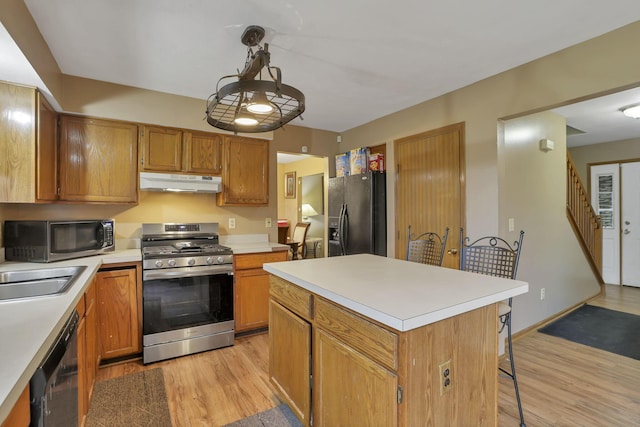 6792 Makady Rd, Canal Winchester, OH 43110 - kitchen featuring black appliances, under cabinet range hood, light wood-style floors, light countertops, and a kitchen breakfast bar