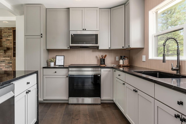 1071 US-42, London, OH 43140 - kitchen with stainless steel appliances, a sink, dark wood-style floors, tasteful backsplash, and dark stone counters