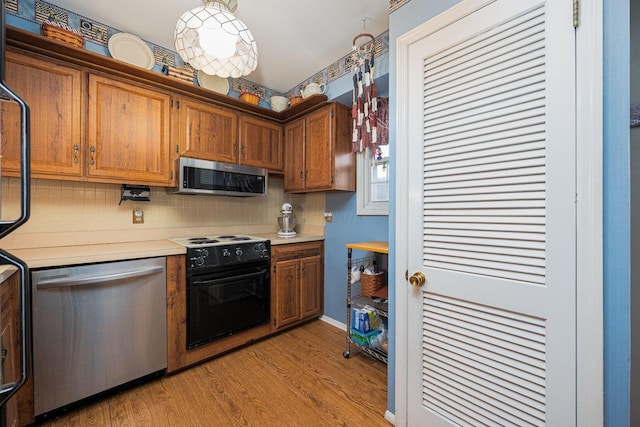 2349 Hardesty Dr N Unit B9, Columbus, OH 43204 - kitchen with stainless steel appliances, light countertops, brown cabinets, backsplash, and light wood finished floors